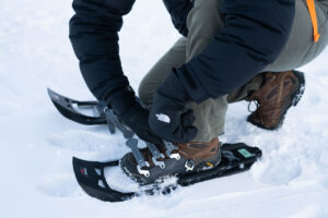 person strapping on snowshies