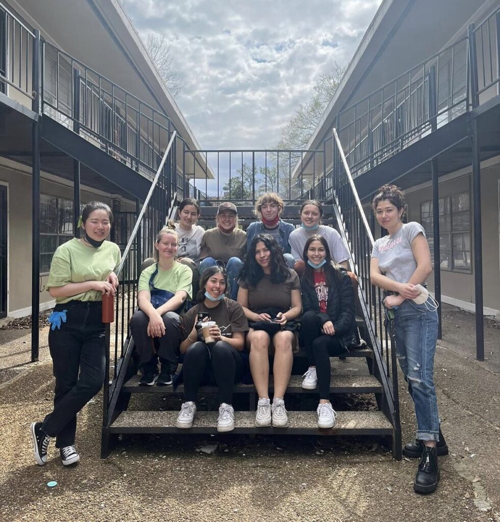 A group of students sit on the steps outside a building on an Alternative Breaks trip.