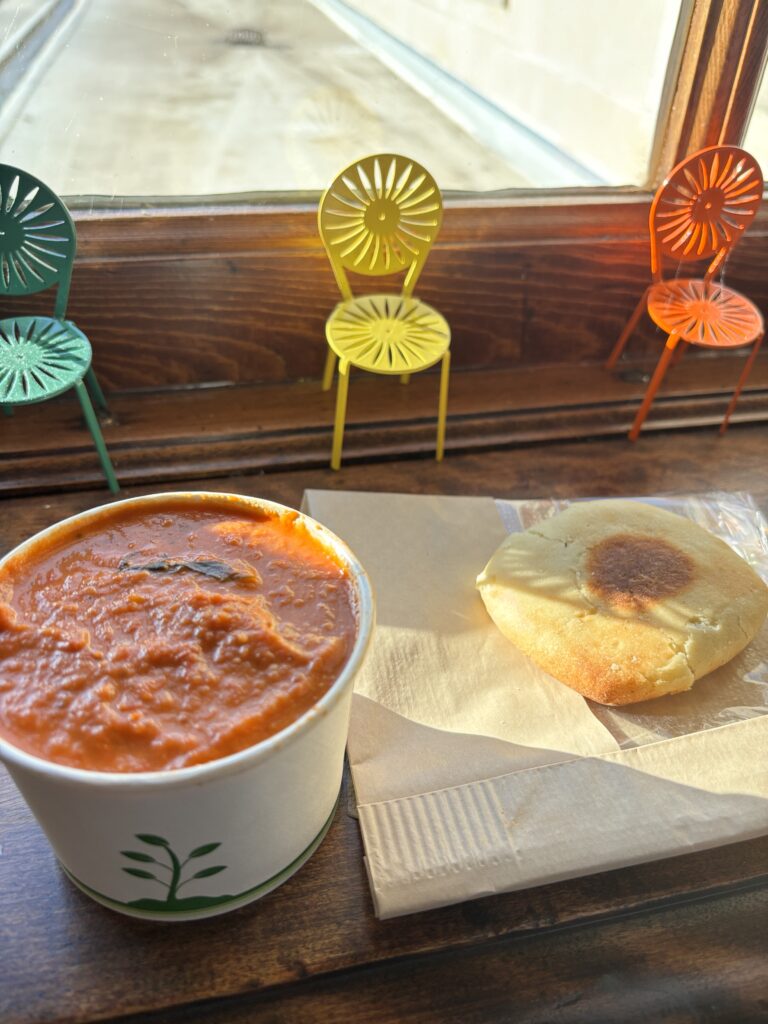 tomato soup next to bread with three mini terrace chairs in background
