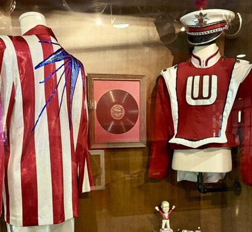 sparkly jacket, marching band uniform and other band materials in display case 