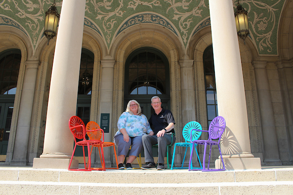 mark sits with wife amy guthier on chairs in front of memorial union